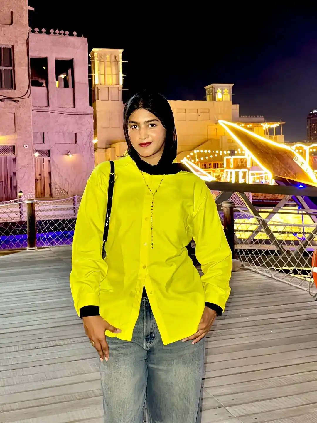 Best Digital Marketer in Kochi wearing a bright yellow shirt and black headscarf, standing outdoors with a modern urban background at night.
